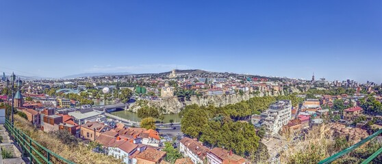 Panoramic daytime view over the city of Tbilisi, Georgia, with colorful rooftops and landmarks