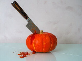 hokkaido pumpkin with a knife stuck in the middle, light background, lots of knife, red elements of...