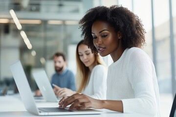An engaged and diverse team collaborates around laptops in a bright, open-plan office, reflecting teamwork, innovation, and productivity in a modern work culture.