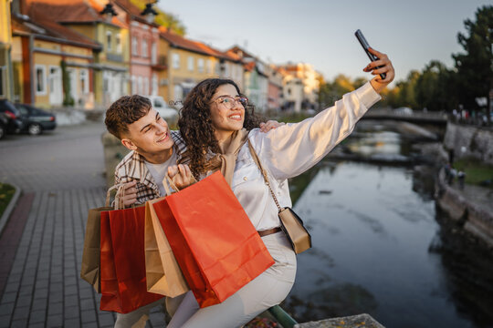Girlfriend take a self portrait with her boyfriend hold shopping bags