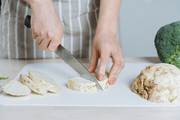 Chef Slicing Fresh Peeled Celeriac Root on Cutting Board