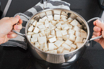 Hands Holding Pot of Boiling Celeriac Cubes for Mashed Preparation