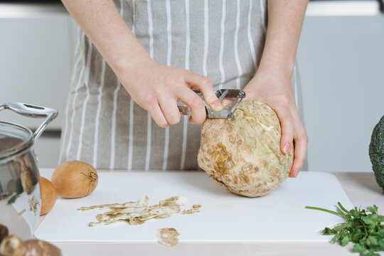 Woman peeling a celery root or celeriac in the kitchen