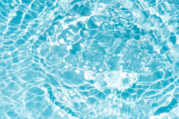 Blue water with ripples on the surface. Defocus blurred transparent blue colored clear calm water surface texture with splashes and bubbles. Water waves with shining pattern texture background.
