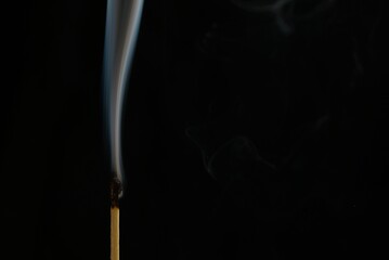 Burnt match with trailing smoke after being blown out on a black background