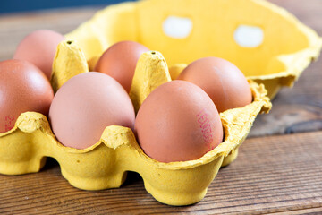 Closeup macro of pasture raised farm fresh dozen brown eggs store bought from farmer in carton box container with speckled eggshells texture
