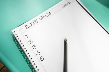 Spiral bound notebook open to a page with handwritten text 2025 Goals and numbered one through five...