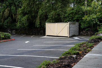 Commercial property parking lot with garbage dumpster enclosure, built from cement blocks and heavy...