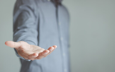 The man is standing and shows an outstretched hand with an open palm. Businessman showing empty...