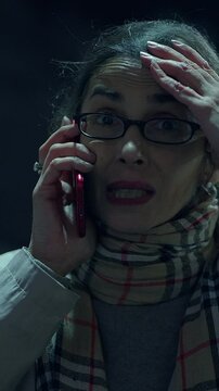 A woman expresses her surprise and emotion while on the phone during the night time hours