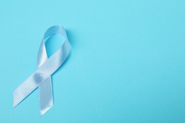 Light blue ribbon on color background, top view with space for text. Prostate cancer awareness