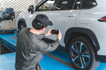 預り車両をスマホで写真を撮る整備士の男性
