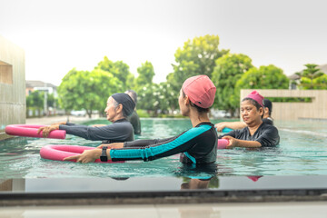 An engaging aquatic exercise class for seniors led by an instructor in a pool. The participants use colorful foam noodles, practicing water-based exercises to stay fit, healthy, and active.