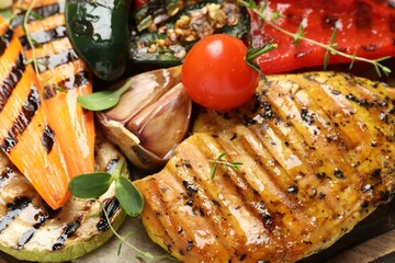 Delicious grilled vegetables and chicken breast on board, closeup