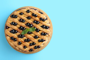 Delicious homemade blueberry pie with mint on light blue background, top view. Space for text