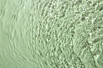 Rippled surface of clear water on light green background, top view