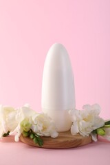 Roll-on deodorant and beautiful eustoma flowers on pink background