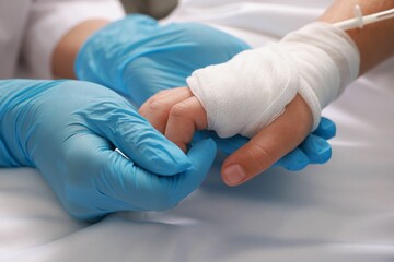 Doctor and child with IV drip in hospital, closeup