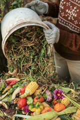 Compost heap pile with bio waste. Farmer hands put weeds grass plants, vegetable fruit scraps from...