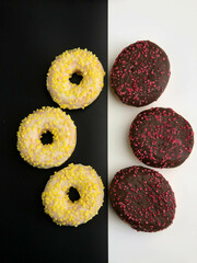 Photo of doughnuts, yellow and pink sprinkled white chocolate doughnuts on a black background; dark red doughnuts covered with chocolate frosted glazed dough, on a white background