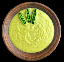 An aerial view photo of a bowl filled with green soup, garnished with three fresh spring peas on top, isolated against a black background