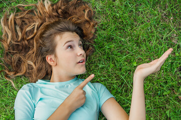 Advertisement concept. Happy beautiful girl with shining smile on green natural grass background...