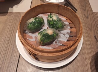 Steamed Green spinach Dumplings in Bamboo Steamer at Chinese Restaurant, Singapore