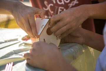 Obraz premium Kids hands making wooden toy house. hobby or leisure. DIY wooden house project.