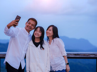 Happy family holding smart phone selfie photo with beautiful mountain landscape nature background.Family spending time together during vacation outdoors.  Concept of happy family.
