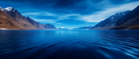 Breathtaking landscape of a serene lake surrounded by majestic mountains under a clear blue sky.