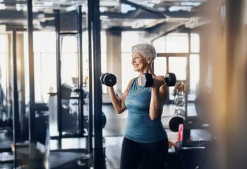 Fototapeta premium A woman in a gym setting, smiling as she lifts dumbbells.