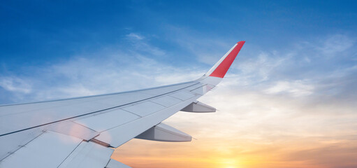 Plane wing view from airplane window inside against scenic sunset or sunrise sky background