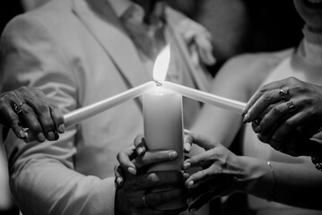 A beautifully captured black and white photo of a newlywed bride and groom lighting candles together in a serene and intimate setting