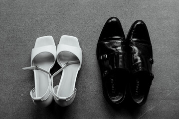 A pair of pristine white shoes and a sleek pair of black shoes are resting closely next to each other on a wooden table