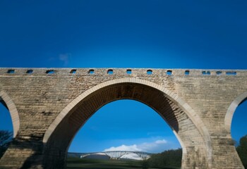 Fototapeta premium Stone arch bridge with a clear blue sky above.