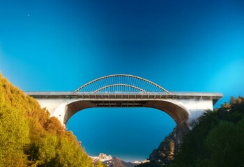 Fototapeta premium A concrete arch bridge with steel support cables against a clear blue sky.