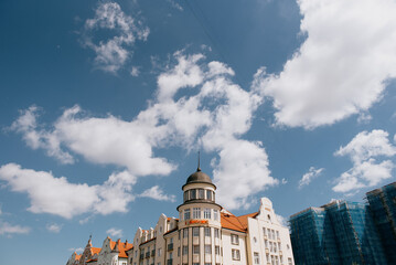 Fototapeta premium A large, impressive building featuring a tall tower located on its rooftop, beautifully set against a clear blue sky scattered with white clouds