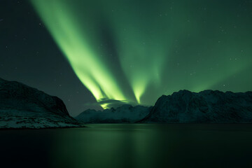 Naklejka premium Breathtaking Northern Lights Illuminating Snowy Mountains and Frozen Lake at Night