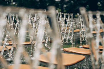A neat array of transparent chairs, each featuring wooden seats, is meticulously arranged in a straight line, creating an elegant display
