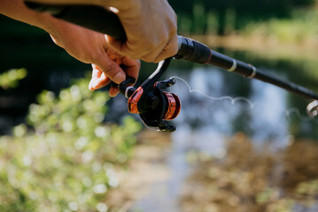 A person is actively holding a fishing rod firmly in their hand, focusing on the surrounding environment and attempting to catch fish