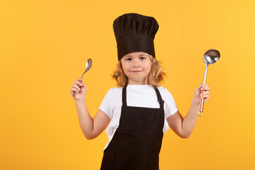 Funny kid chef cook with kitchen ladle and spoon, studio portrait. Chef child preparing healthy...