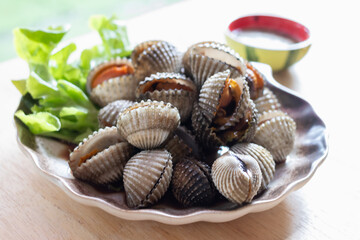 Cooked cockle on plate usually serve with spicy seafood sauce, menu from sea shell. Semi-cooked raw food.