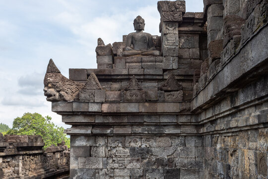 Wall with old religious stone statues in Borobudur Temple in Indonesia under blue coudy sky