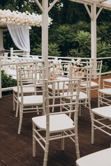 A neat row of pristine white chairs is perfectly lined up along a beautifully crafted wooden deck, creating an inviting atmosphere