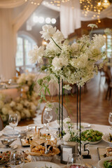 A beautifully arranged table set up for a wedding reception featuring elegant white flowers displayed in tall and decorative vases