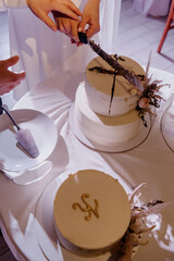 A loving couple is joyfully cutting a beautiful wedding cake that is elegantly placed on a table, surrounded by festive decorations