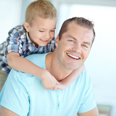 Boy, father and piggy back on sofa in home for portrait, bonding or love for games, funny or connection in lounge. Child, dad and happy man with comic memory, hug or relax at family house in Germany