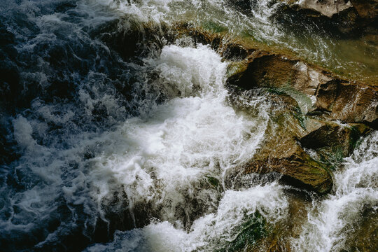 Rushing water cascading over rocky terrain in a natural river setting during daylight hours
