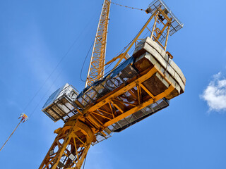 A large yellow crane stands out against a bright blue sky