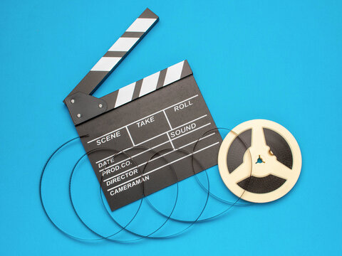 Film Clapperboard and Movie Reel on Blue Background Symbolizing Filmmaking and Cinema
